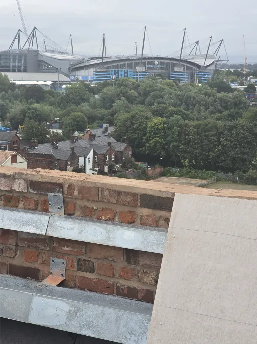 Main roof parapet installation at Brunswick Mill with the Etihad Stadium behind